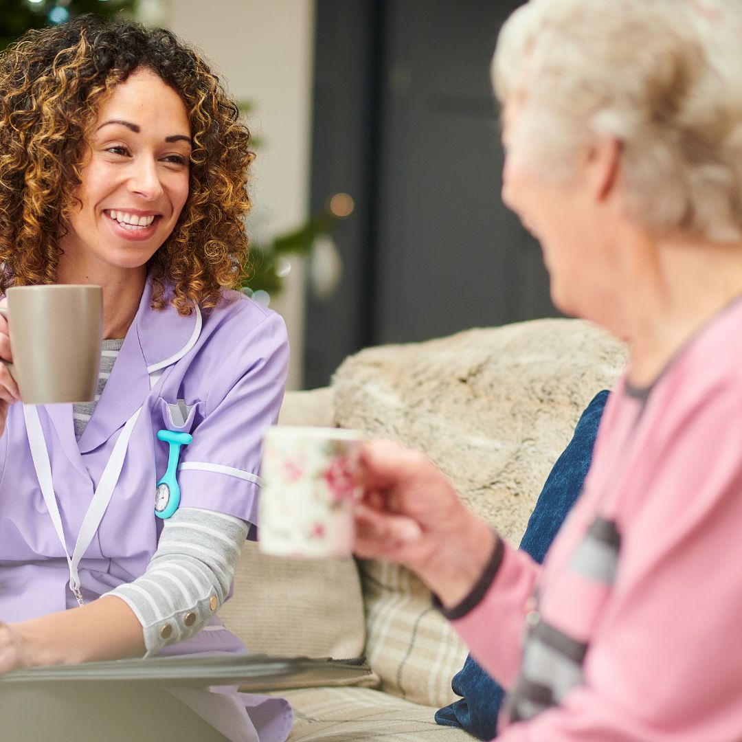 caregiver having coffee with senior citizen 